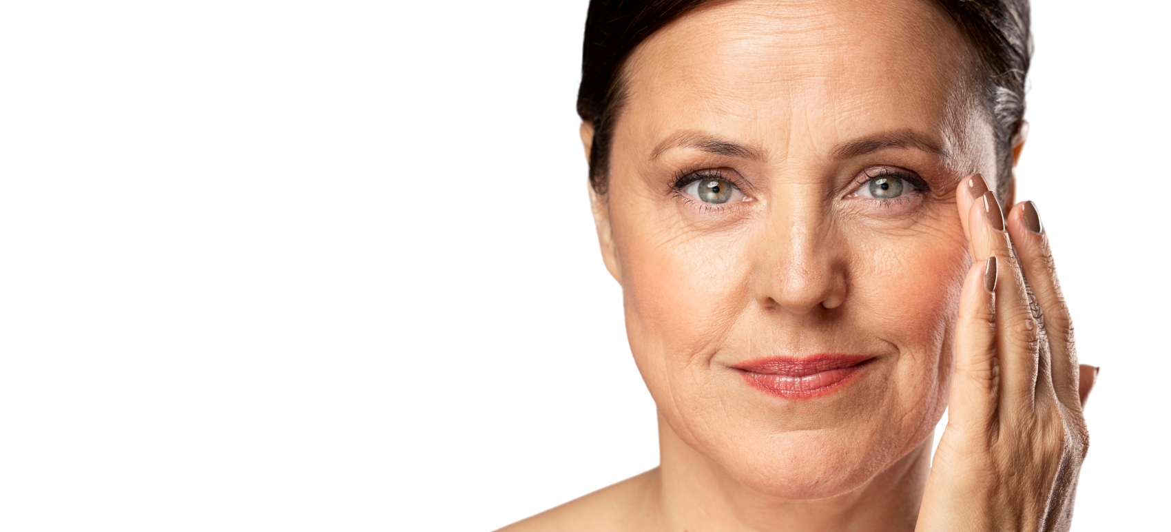 Juläine, Reife Frau berührt sanft ihre Wangen- und Augenpartie mit feinen Falten