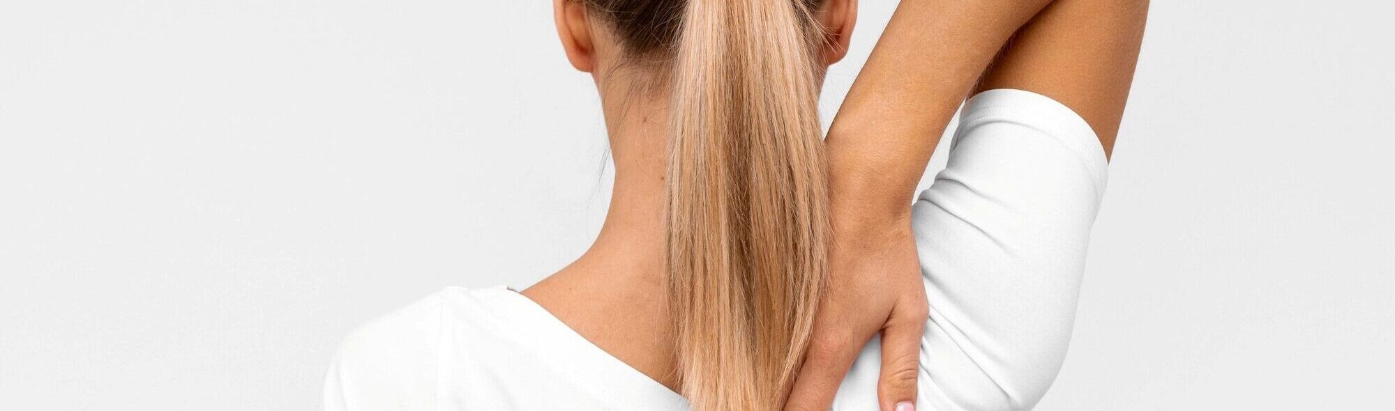 Trapezius-Botox, Frau greift sich an den verspannten Nacken- und Trapezmuskelbereich zur Verdeutlichung von Schulterschmerzen